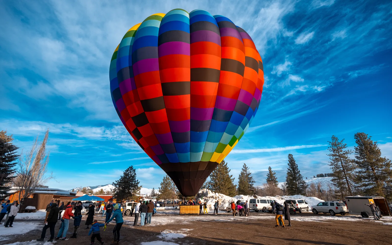 Colorful hot air balloons rising at dawn over snow-dusted landscape during annual balloon roundup